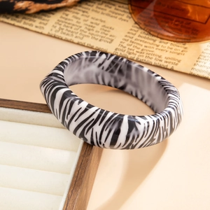 Détail d'un large bracelet en résine zébrée sur boîte à bijoux avec journal vintage