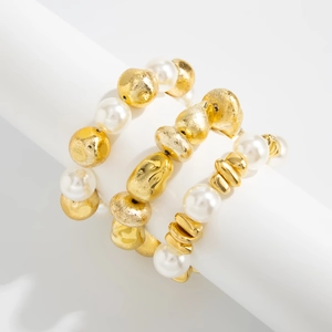 Detailed shot of three elastic beaded bracelets featuring gold textured beads and pearls