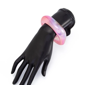 Nahaufnahme eines rosa schillernden Harzarmreifs mit holografischem Finish auf Ständer