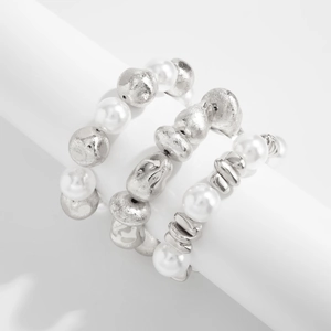Detail of silver textured metal beads and white pearls on stacked elastic rings