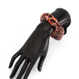 Gros plan d'un large bracelet en résine léopard sur main de mannequin, texture écaillée marron