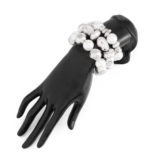Detail of layered silver beaded bracelet with oversized pearls on a hand display