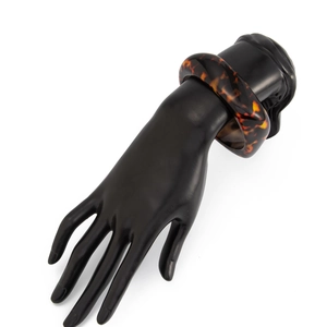 Gros plan d'un large bracelet en résine polie à motif léopard sur support noir