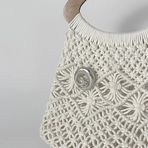 Dettaglio borsa macramè con motivo floreale intrecciato e chiusura a spirale in metallo