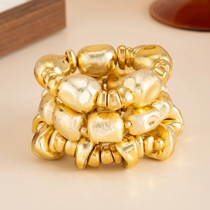 Detailed macro view of layered gold beads with hammered texture and vintage metallic luster