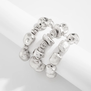 Close-up of three-piece silver beaded elastic bracelets with matte hammered texture