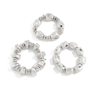 Close-up of three silver irregular hammered metal rings with a textured pebble design