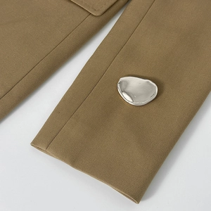 Macro di una spilla a cigno in metallo liquido su tessuto in twill kaki con dettagli