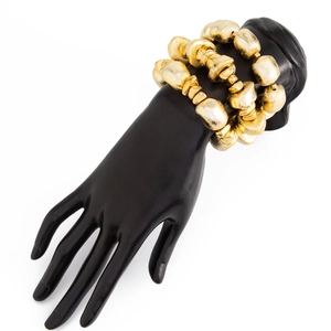 Close-up of golden beaded bracelets with irregular matte textures on black hand model