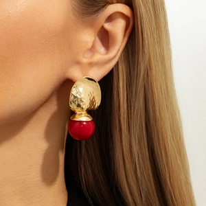 Gros plan de boucles d'oreilles cœur en métal martelé doré avec perles en résine rouge