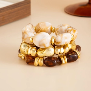 Detail of layered resin marble and gold textured metal beads on elastic bracelets