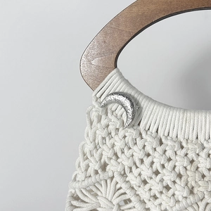 Dettaglio borsa in macramè con trama geometrica, chiusura a luna e manico in legno