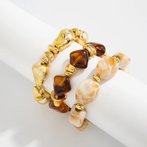 Detailed macro of vintage beaded resin and frosted gold-toned elastic bracelets set