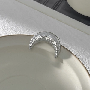 Dettaglio della spilla a mezzaluna argento con finitura martellata su bordo ceramica