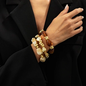 Detail of retro layered beaded bracelets with amber resin and gold irregular beads