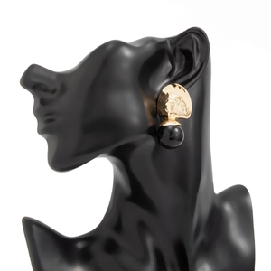 Detail von goldenen Ohrhängern aus Hammerschlag-Metall mit schwarzer Harzperle