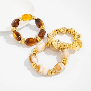 Detail of three-piece stretch bracelet set with amber resin beads and gold metallic pieces
