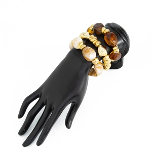 Macro view of golden CCB beads and amber resin charms on a multi-layer stretch bracelet