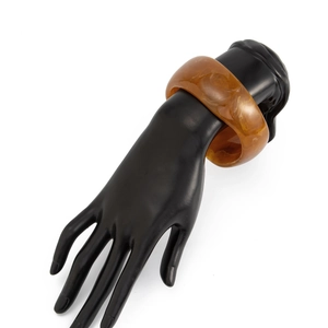 Makro-Detail des bernsteinfarbenen Harzarmreifs mit Marmortextur am Handmodell