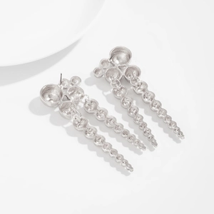 Détail de boucles d'oreilles pendantes argentées avec clous sphériques et perles ondulées