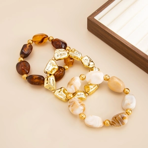 Macro detail of elastic beaded bracelets with amber resin and irregular gold beads