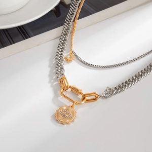 Detail of layered sunburst and star pendant necklace with gold D-ring clasp on white setup