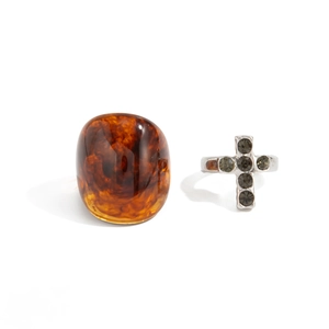 Detailed shot of amber resin oval ring and silver cross ring with grey rhinestones