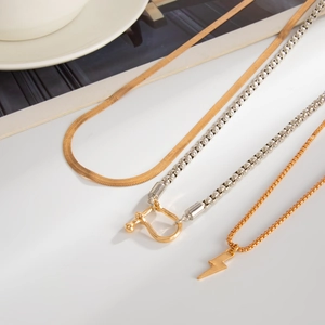 Close-up of layered gold snake chain, U-link square chain, and lightning bolt pendant necklace