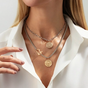 Layered necklace set featuring gold compass and emblem pendants on mixed silver chains