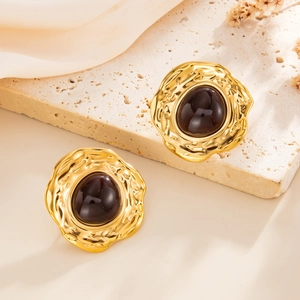 Close-up of vintage gold hammered metal earrings with large dark resin gemstones