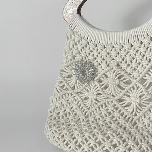 Dettaglio macro della borsa in macramè con ornamento metallico a forma di sole