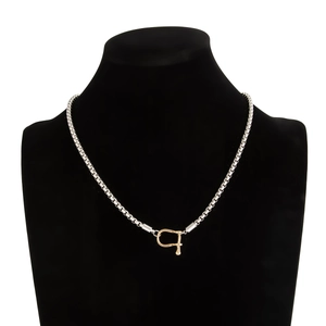 Detail view of two-tone U-shape shackle clasp and box chain necklace on black bust