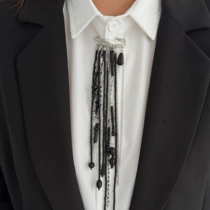 Detail showing vintage punk silver safety pin brooch with black bead tassel on a blazer