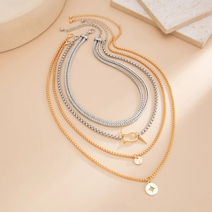 Detail of layered gold and silver chains with horsebit, compass and round coin charms