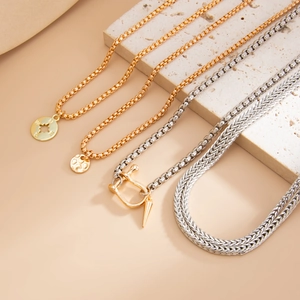 Macro detail of gold compass pendant and silver spike necklaces on textured stone
