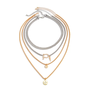 Close-up of four-layer mixed metal necklace with compass and textured disc pendants