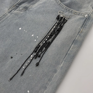 Detail of beaded long tassel brooch with black beads and silver chains on denim pocket