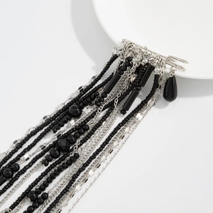 Detail of fashion safety pin brooch with black beads, silver chains and teardrop charm