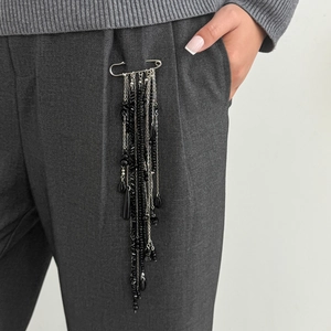 Détail d'une broche épingle à longues pampilles noires perlées sur une poche de veste