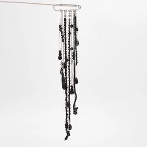 Macro detail of multilayered black crystal beads and silver tassel chain brooch pin