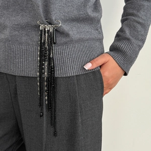 Detail of silver safety pin brooch with black bead fringe on grey knitwear clothing