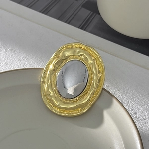 Dettaglio della spilla ovale a pieghe liquide con texture martellate in oro e argento