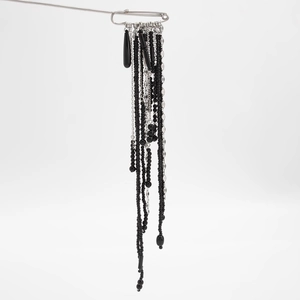 Close-up of hip-hop style beaded tassel brooch with silver chains and black crystals