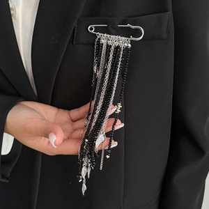 Détail de broche épingle de nourrice argentée avec glands de perles noires sur costume