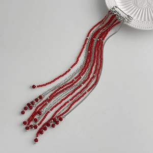 Macro detail of silver safety pin brooch with multi-layered red crystal bead tassel chains