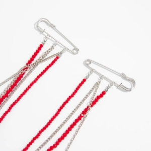 Détail de la broche épingle avec chaînes argentées et perles de cristal rouge à facettes