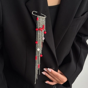 Détail de la broche épingle à nourrice argentée avec de longs glands et perles rouges