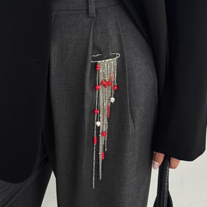 Détail d'une broche à pampilles métalliques, pendentif cheval rouge et perles colorées