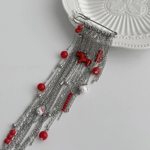 Détail de la broche épingle à nourrice argentée avec perles rouges et longues chaînes