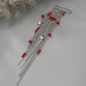 Détail de broche bohème argentée avec breloque cheval rouge et pompons en chaîne